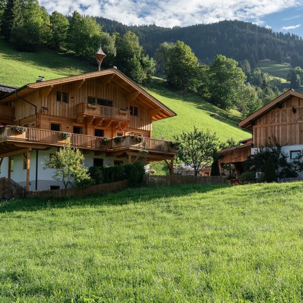 The charming farmstay nestled in a lush green meadow, surrounded by scenic alpine hills.