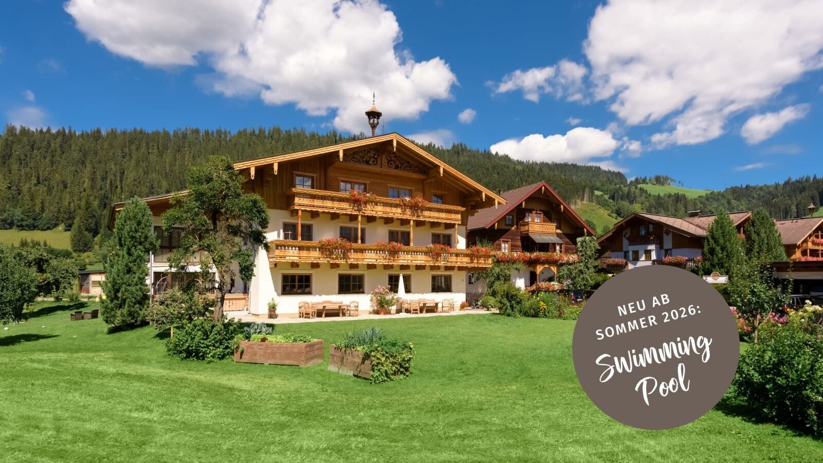 The two traditional farmhouses with balconies, set amidst a green lawn and mountain landscape.