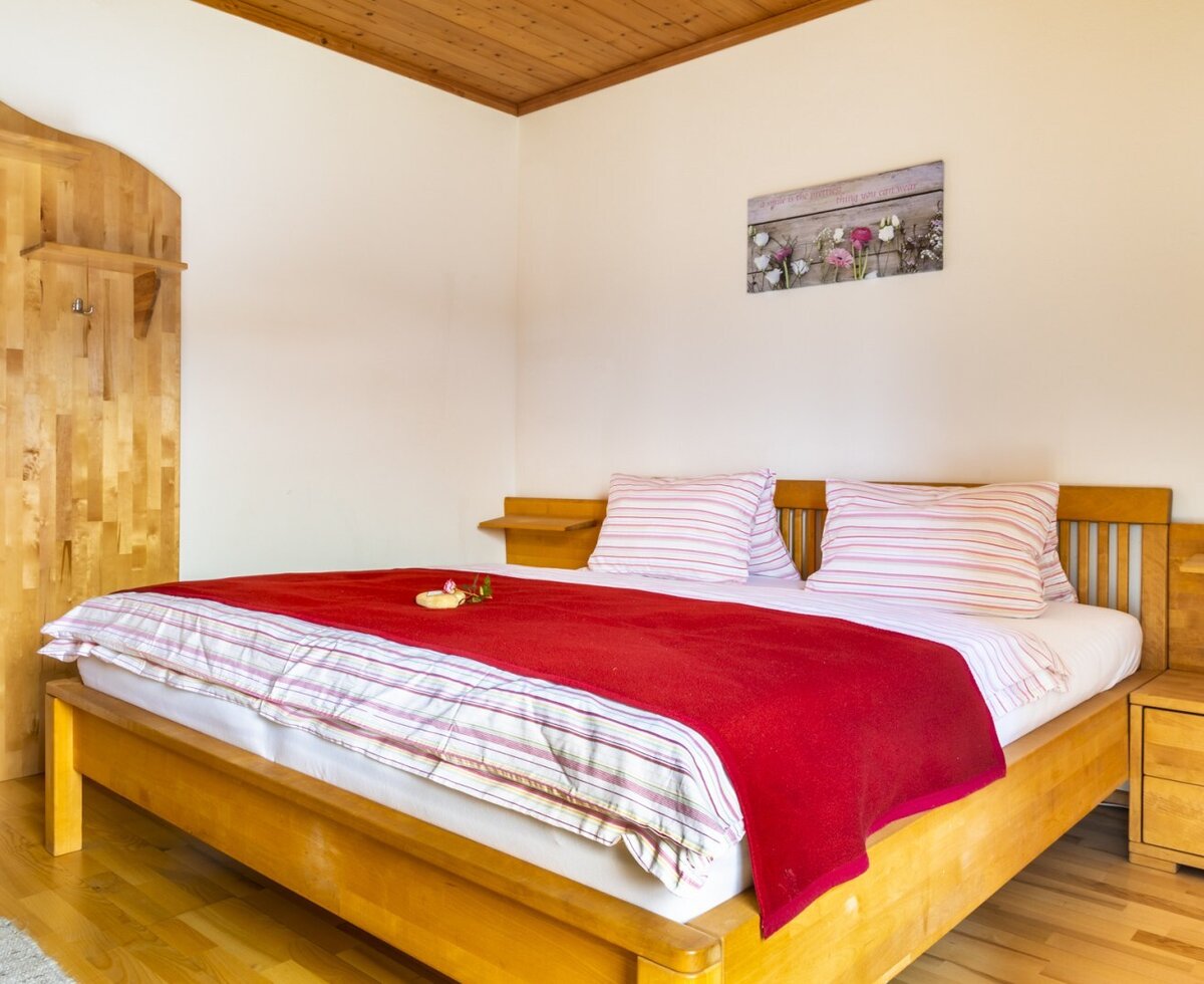 Bedroom in the Farm House featuring a wooden double bed, integrated bedside tables, and a wooden wall panel with hooks.