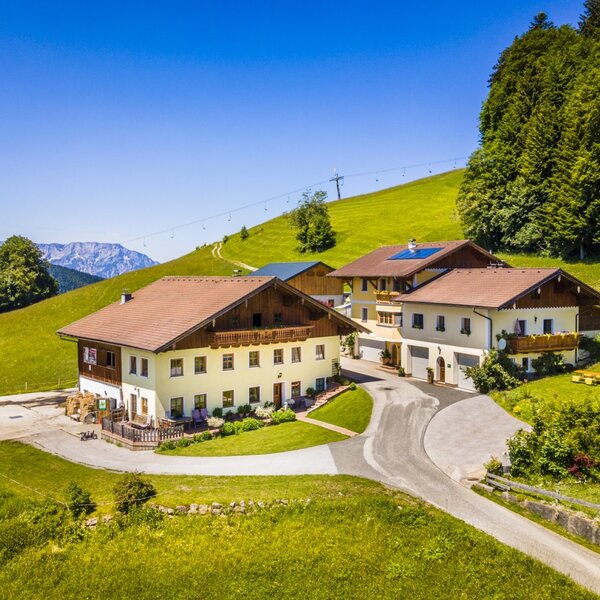The Reitlhof Farm House, featuring several buildings, is located on a green hillside with distant mountain views.
