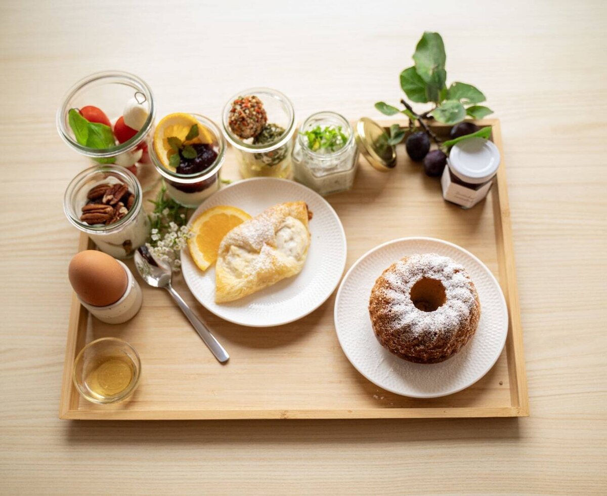Enjoy a varied breakfast at the Farm House, served on a tray with an egg, honey, yogurt, savory spreads, pastries, and a small cake.
