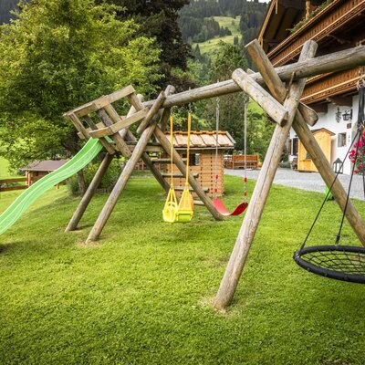 The farmhouse's inviting children's playground featuring a slide, swings, and a small playhouse on a green lawn.