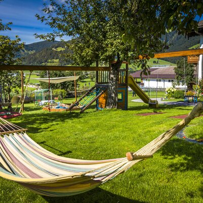 The garden at the Farm House features a children's playground with a slide, swing set, sandbox, and a hammock.