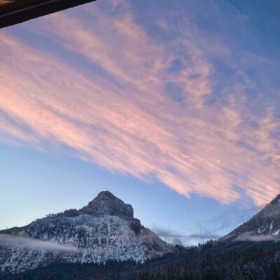 View of snow-covered mountains and a sky with pink clouds from the Farm House balcony.