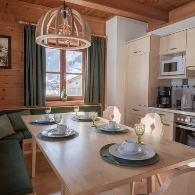 Kitchen and dining area in the farmhouse featuring a set wooden dining table, a corner bench, and a fully equipped kitchenette with a microwave and stove.