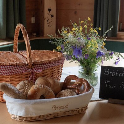 The farmhouse offers a bread roll service, with a basket of fresh rolls and pretzels displayed alongside a picnic basket.