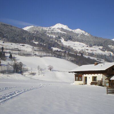 The farm house exterior in a snow-covered mountain landscape.