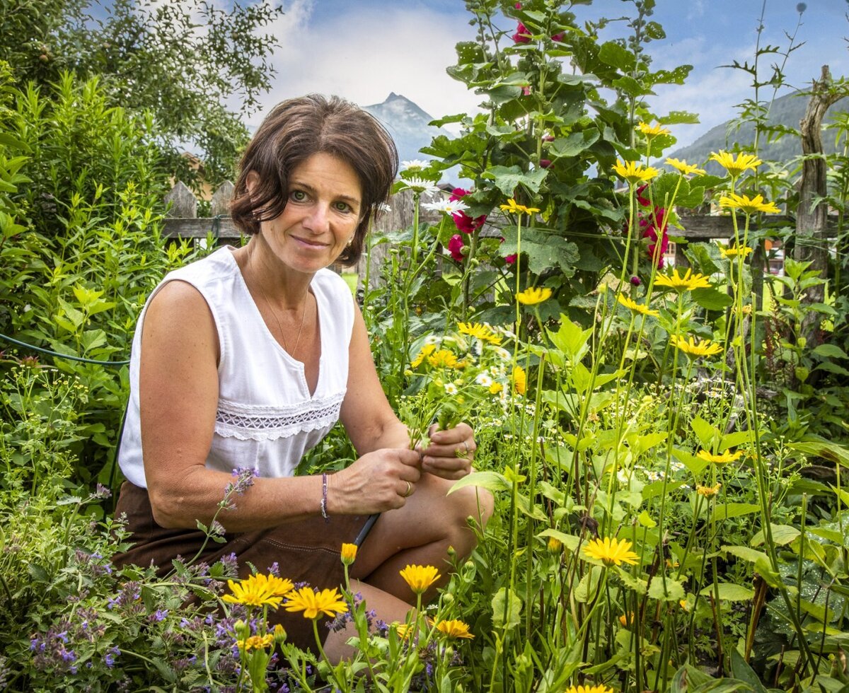 The farmhouse's idyllic cottage garden filled with colorful summer flowers and scenic mountain views.