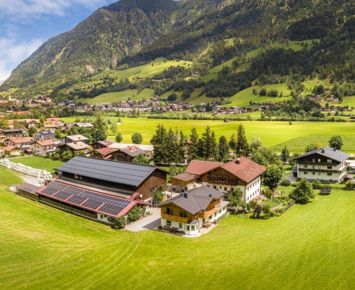The idyllic farmhouse nestled in lush green meadows, offering a beautiful view of the surrounding Alps.