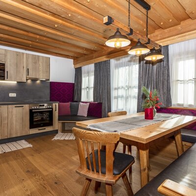 Fully equipped kitchen area with electric stove and oven, connected to the dining area featuring a wooden table and bench seating in the Farm House.