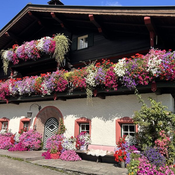 Exterior view of the farmhouse with multiple balconies richly decorated with colorful flowers.
