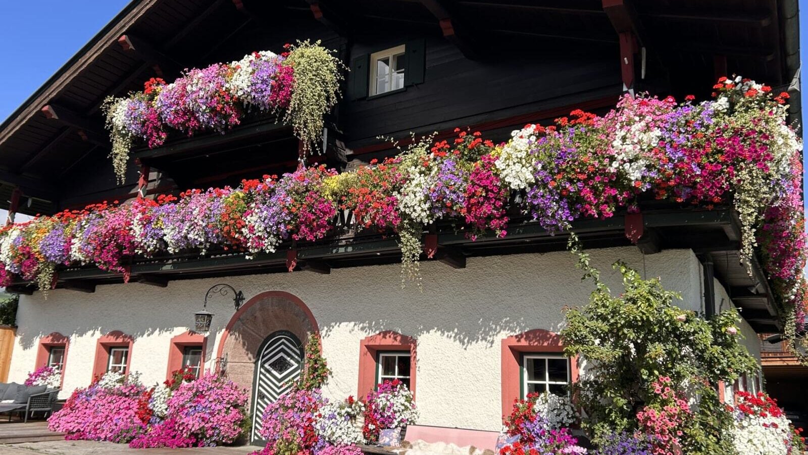 Exterior view of the farmhouse with multiple balconies richly decorated with colorful flowers.