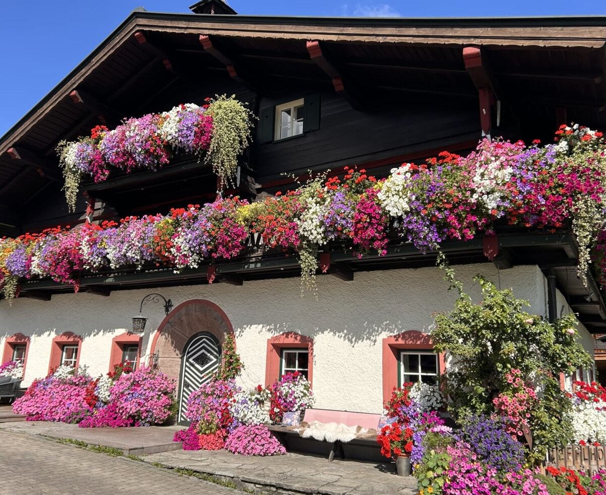 Exterior view of the farmhouse with multiple balconies richly decorated with colorful flowers.