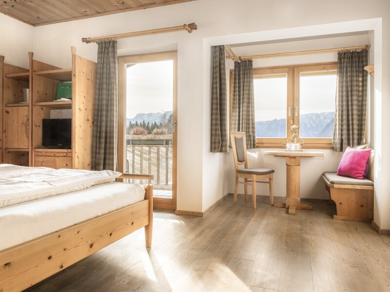 Double room with TV, access to the balcony and a seating area with mountain views.