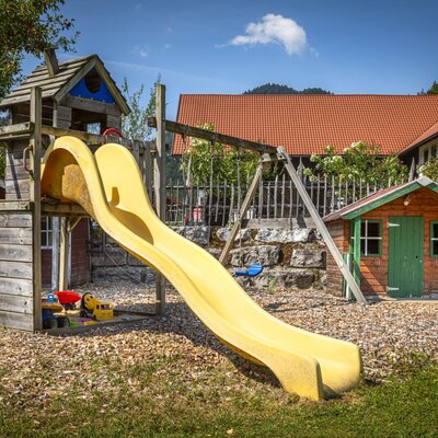 Playground at the Ferienwohnung with a slide, swing, and playhouse.