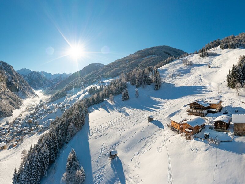 The farmhouse in a snow-covered winter landscape with a view of the valley and the surrounding mountains.