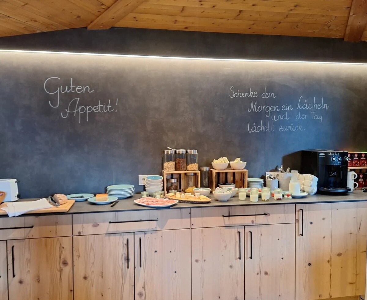 The breakfast buffet in the common room of the farmhouse, offering a selection of cold cuts, cheese, cereals, and fresh bread.