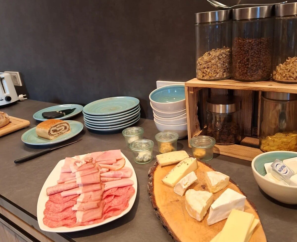 Breakfast buffet at the farmhouse with cold cuts, cheese, poppy seed roll, and muesli.