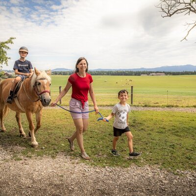 An exciting pony ride for children on the welcoming farm, set against a scenic mountain backdrop.