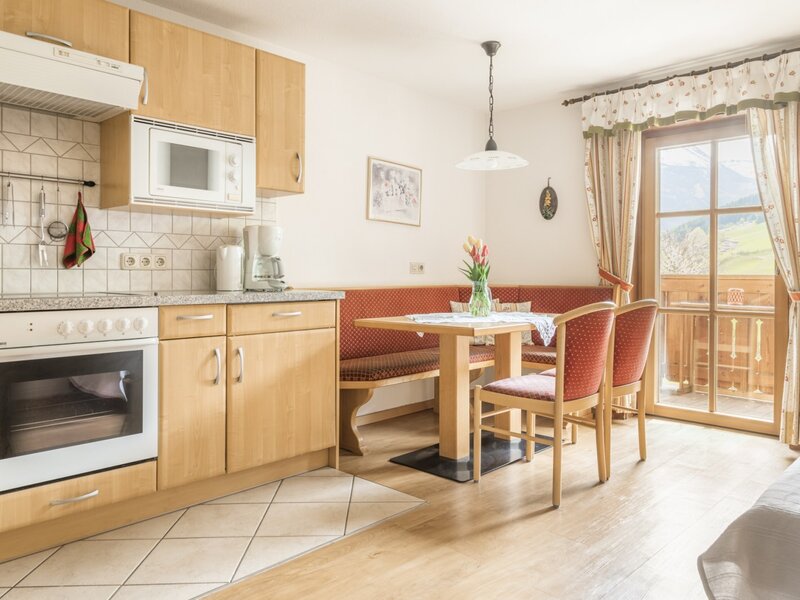 Fully equipped kitchen and dining area in the farmhouse with balcony access and mountain views.