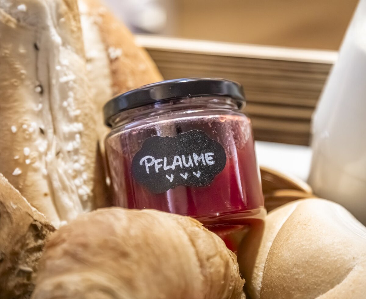 Farmhouse breakfast featuring fresh bread, rolls, a croissant, plum jam, and milk.