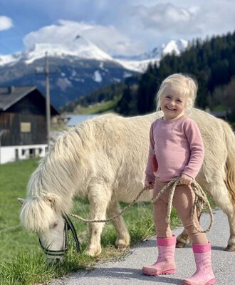 A family-friendly experience at the farmhouse, featuring a gentle pony against a scenic mountain backdrop.