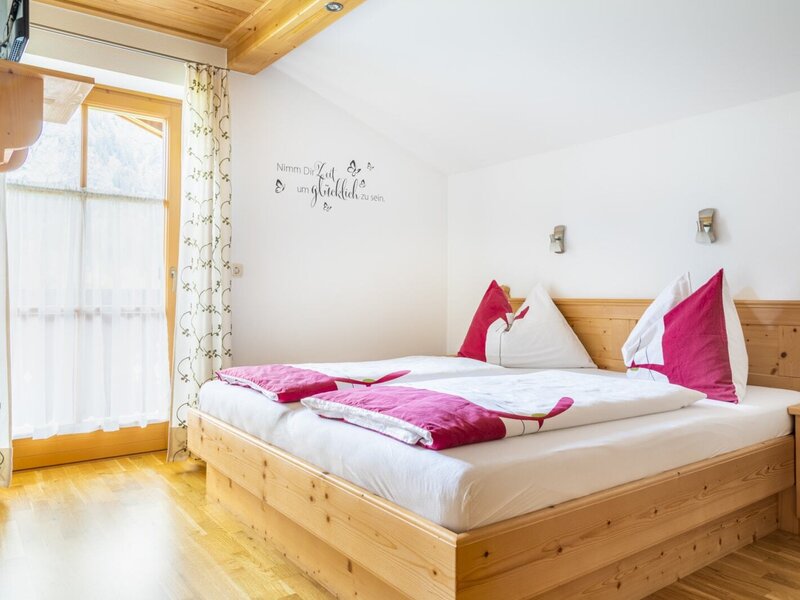Double bedroom in the Farm House featuring a wooden bed, wood-paneled ceiling, and a glass door with outdoor access.