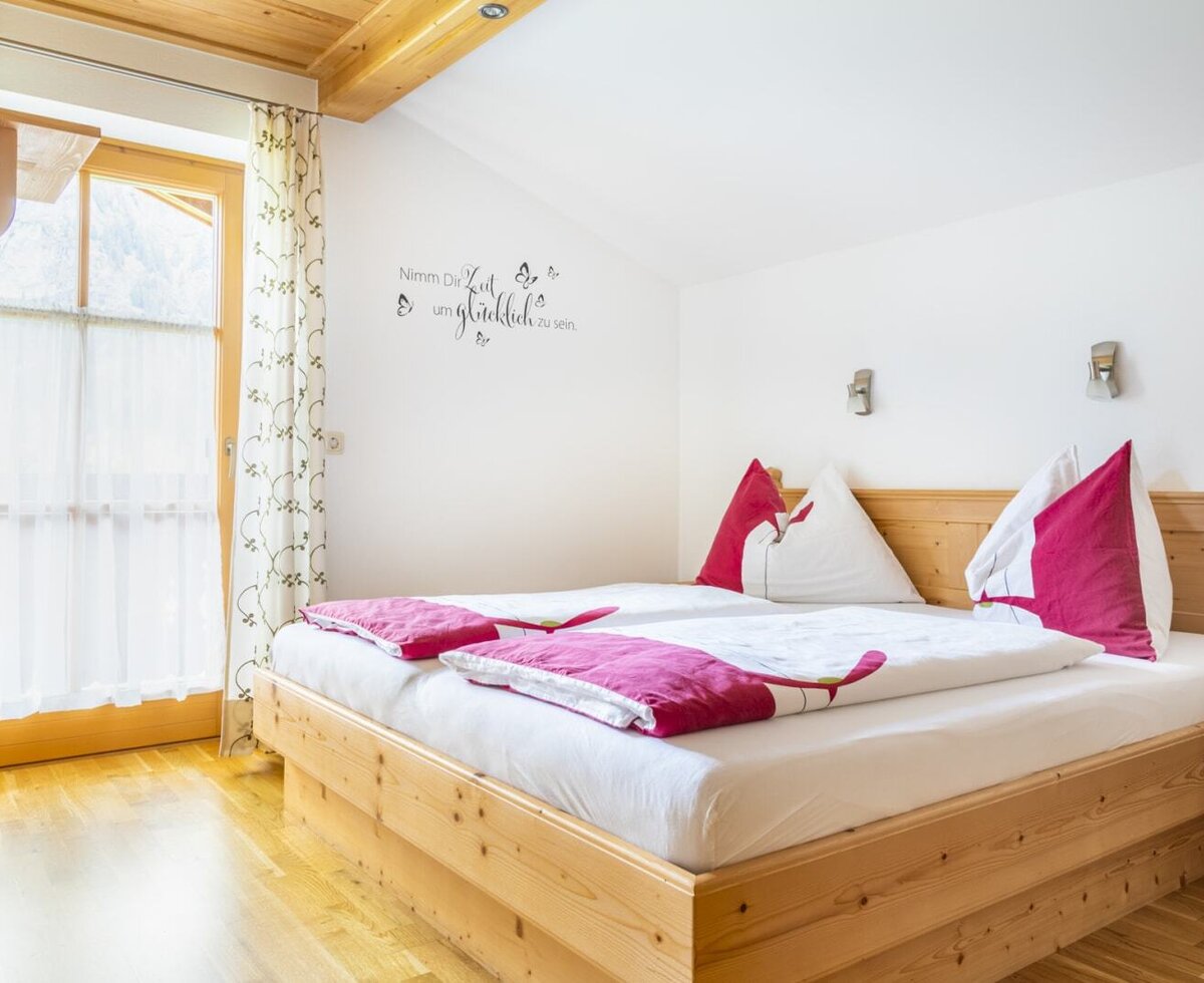 Double bedroom in the Farm House featuring a wooden bed, wood-paneled ceiling, and a glass door with outdoor access.