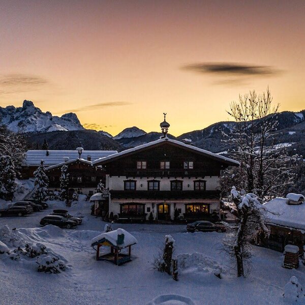 The Farm House exterior in a snow-covered winter landscape, featuring mountain views and outdoor parking.