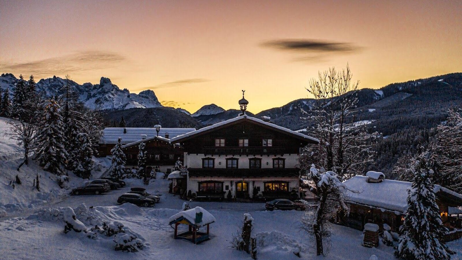 The Farm House exterior in a snow-covered winter landscape, featuring mountain views and outdoor parking.