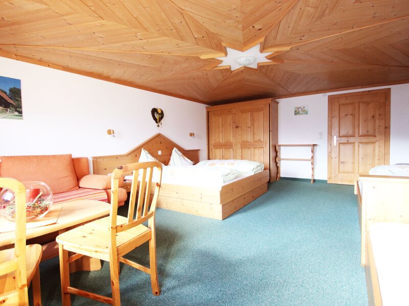 Ferienwohnung sleeping and living area with a double bed, sofa, coffee table, wooden furniture, and a wooden ceiling.