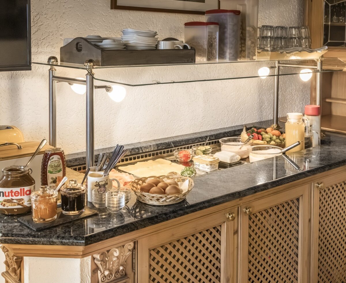 Ferienwohnung breakfast buffet featuring a selection of cold cuts, cheese, jams, Nutella, honey, eggs, fruit, yogurt, and juices.