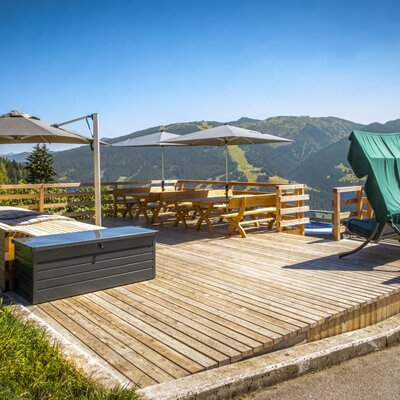 The Ferienwohnung's sunny wooden terrace features cozy seating areas, sun loungers, and magnificent mountain views.