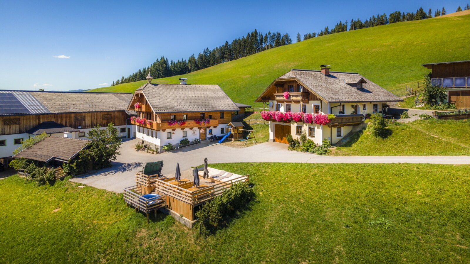 The inviting Ferienwohnung nestled in an idyllic mountain landscape with spacious lawns and a sunny wooden terrace.
