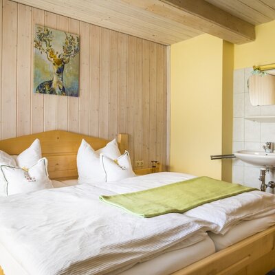 Double bedroom in the Farm House with a wooden bed, wood-paneled walls, and an integrated sink and mirror.