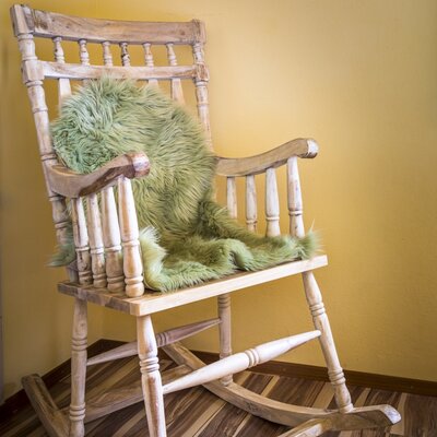 Wooden rocking chair with a green furry throw in the farm house.