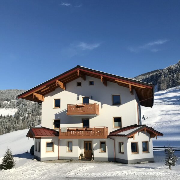 The multi-story Bio Schartenhof farm house exterior with balconies, set against snow-covered landscapes in winter.