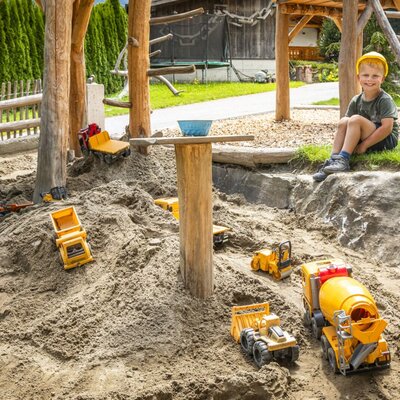 An inviting play area at the farmhouse featuring a spacious sandbox and plenty of colorful toy vehicles.