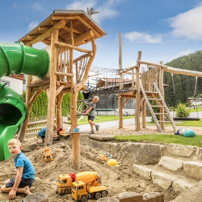 The farmhouse's inviting children's playground with a large slide, a sandpit, and wooden climbing structures.