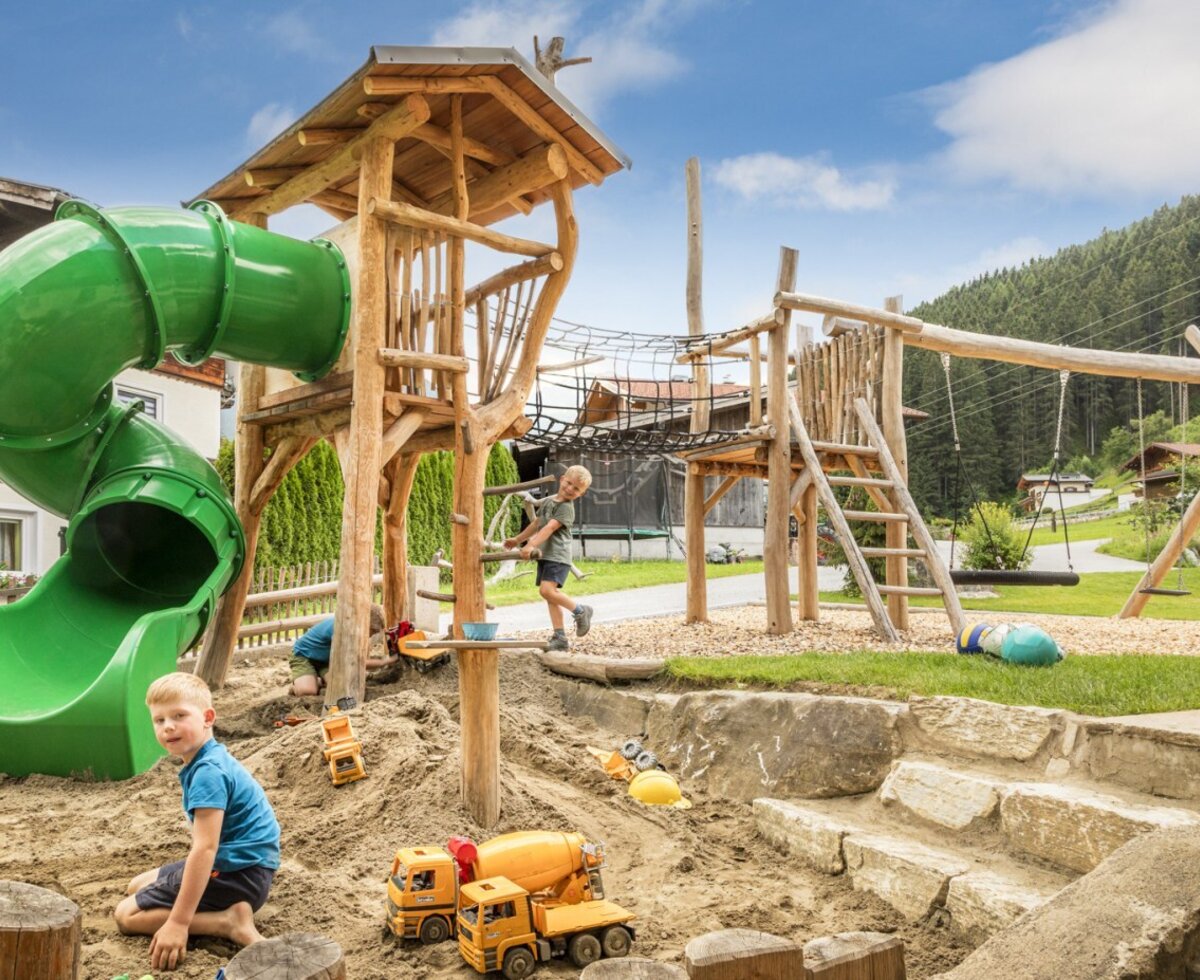 The farmhouse's inviting children's playground with a large slide, a sandpit, and wooden climbing structures.