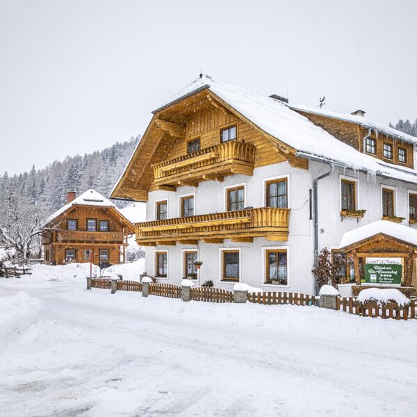 The Farm House exterior, showcasing its traditional wooden balconies and the surrounding snow-covered winter landscape.