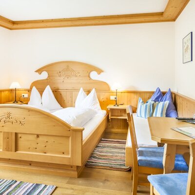 Double room in the Farm House featuring a solid wood double bed and an integrated dining area with a corner bench.