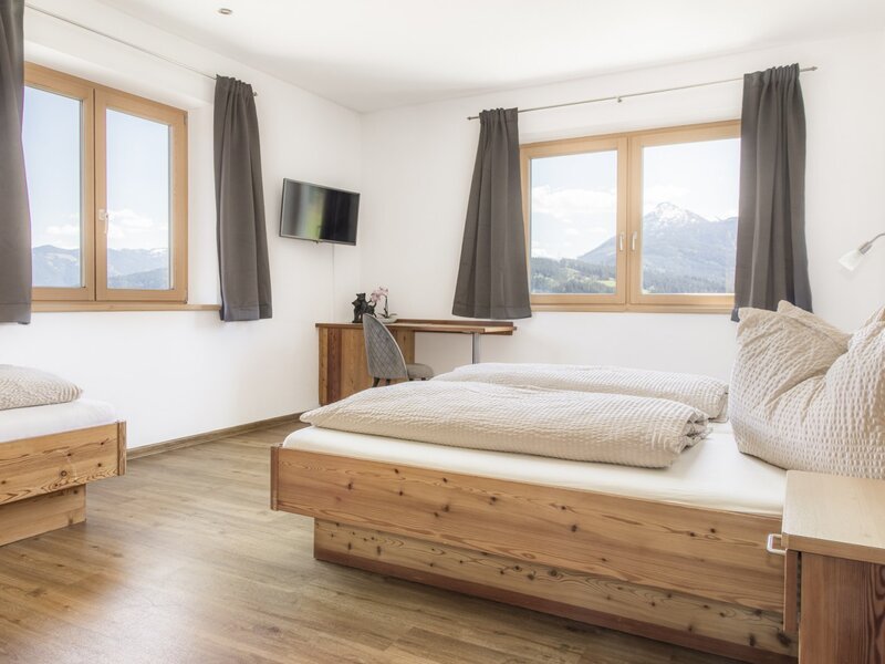 Bedroom with a double bed, a single bed, a desk, and mountain views.