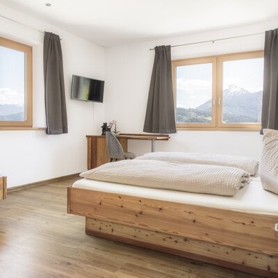 Bedroom with a double bed, a single bed, a desk, and mountain views.