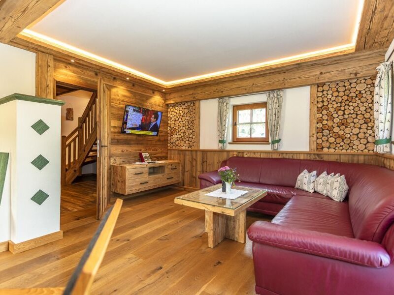 Living area in the Bed and Breakfast with a red corner sofa, wooden floor, TV, and access to the staircase.