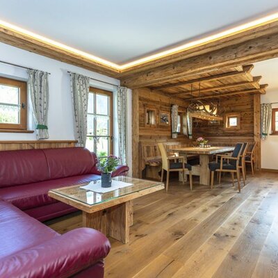Living and dining area in the Bed and Breakfast with a red corner sofa, wooden coffee table, and dining set.