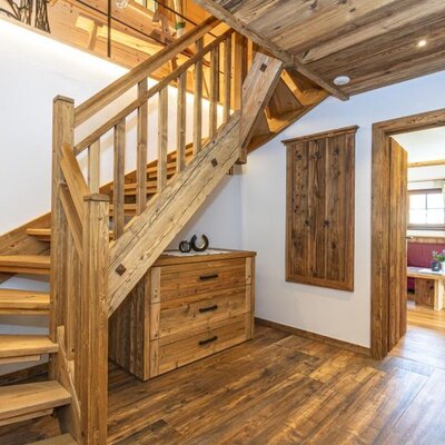 Wooden staircase with a wooden chest of drawers underneath and a doorway to another room in the Bed and Breakfast.