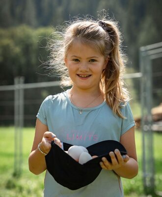A young girl holds a hat with collected eggs, an activity for guests at the Bed and Breakfast.