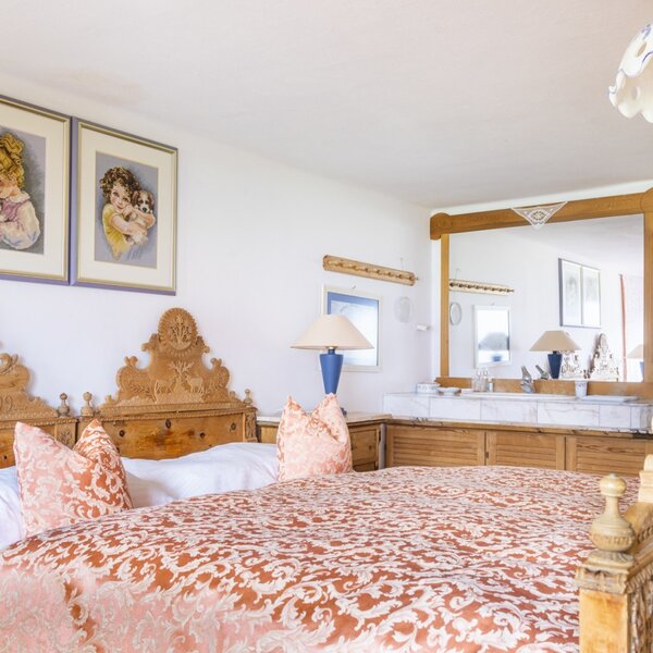 Double bedroom in the vacation rental featuring a carved wooden bed and a vanity area with a mirror and washbasin. Double bedroom in the vacation rental featuring a carved wooden bed and a vanity area with a mirror and washbasin.