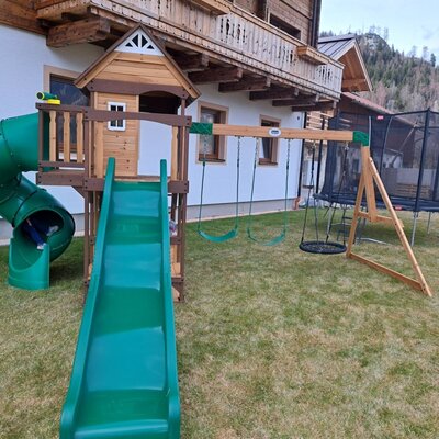 The children's playground at the Bed and Breakfast, featuring a slide, tunnel slide, swings, and a trampoline.